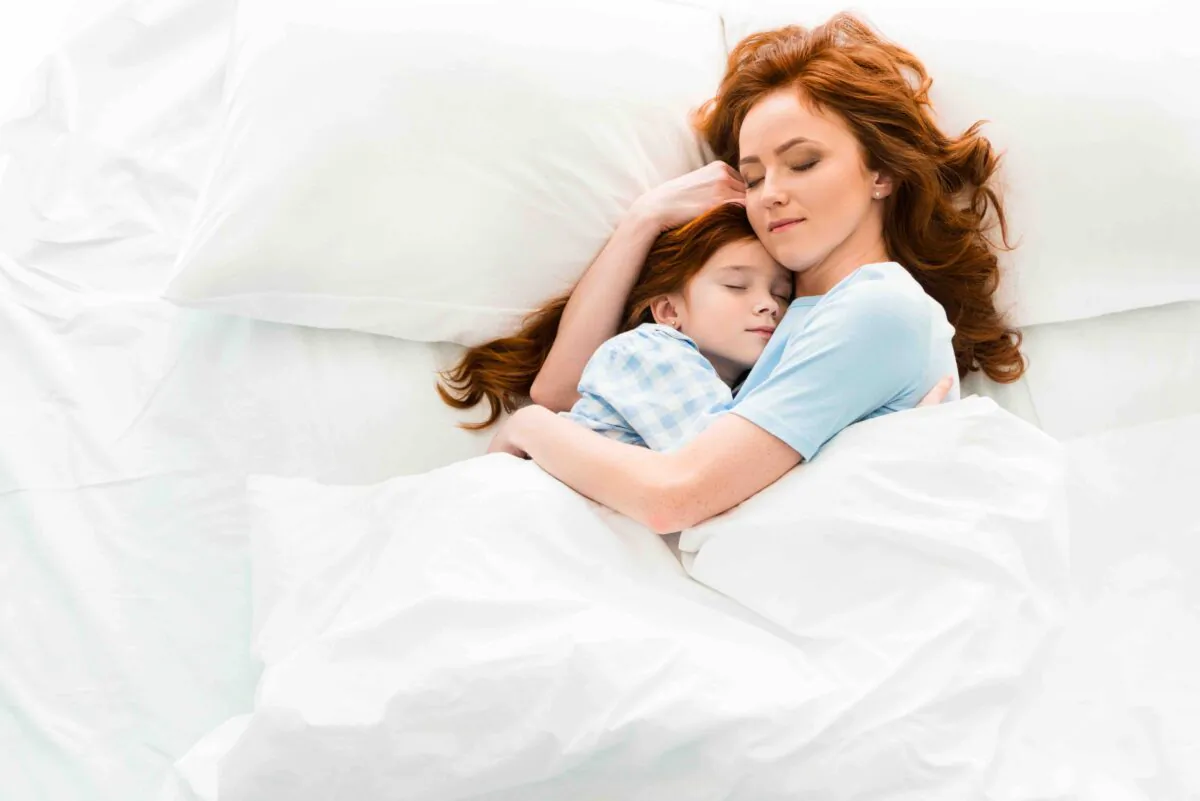 Beautiful mother and daughter hugging and sleeping together in bed. (LightField Studios/Shutterstock)