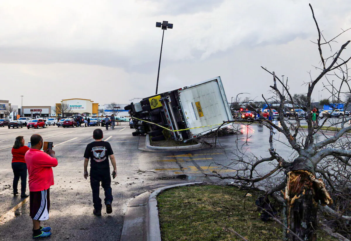 People look at an overturned truck in a parking lot after a previous tornado in a widespread storm system touched down in Round Rock, Texas, on March 21, 2022. (Tamir Kalifa/Reuters)
