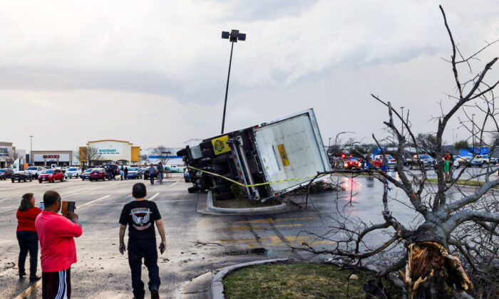 2022 年 3 月 21 日，在德克萨斯州朗德罗克市，一场广泛的风暴系统中的一次龙卷风袭击后，人们在停车场看着一辆翻倒的卡车。（Tamir Kalifa/路透社）