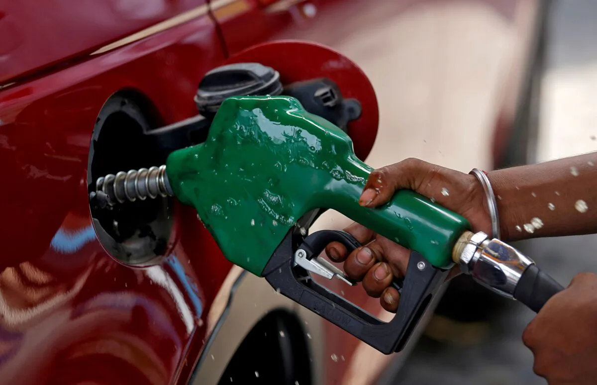 A worker holds a nozzle to pump petrol into a vehicle at a fuel station in Mumbai, India, on May 21, 2018. (Francis Mascarenhas/Reuters)