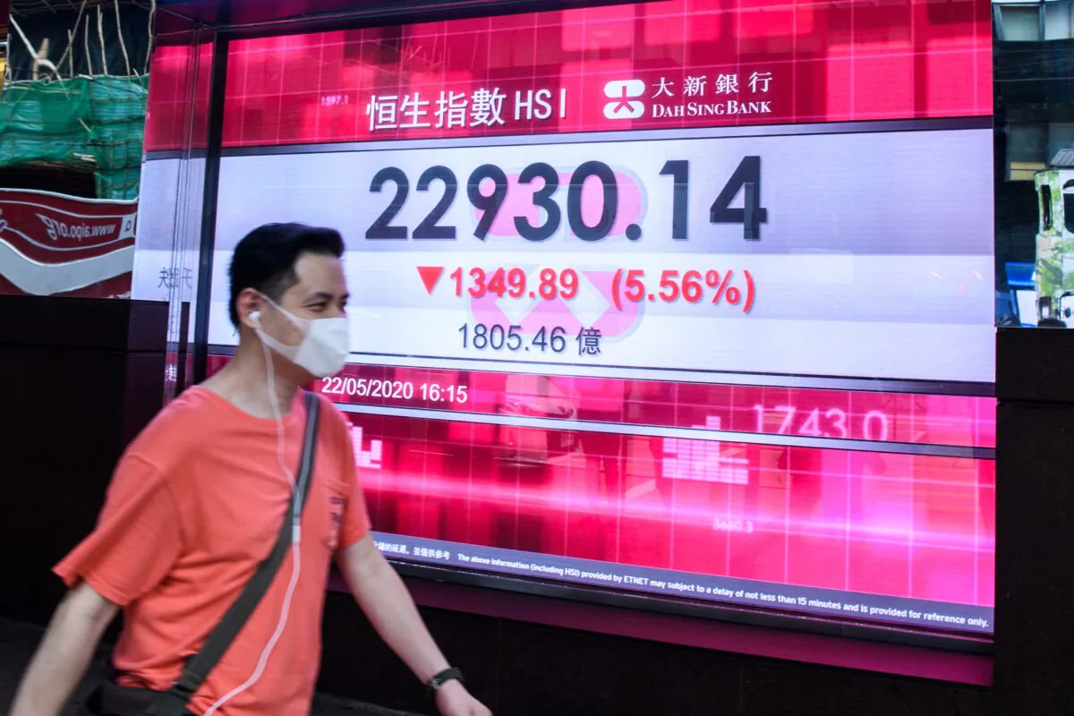 A man walks past a stocks display board showing the Hang Seng Index (HSI) down by 5.56 percent after trading closed for the day in Hong Kong on May 22, 2020. (Anthony Wallace/AFP via Getty Images)