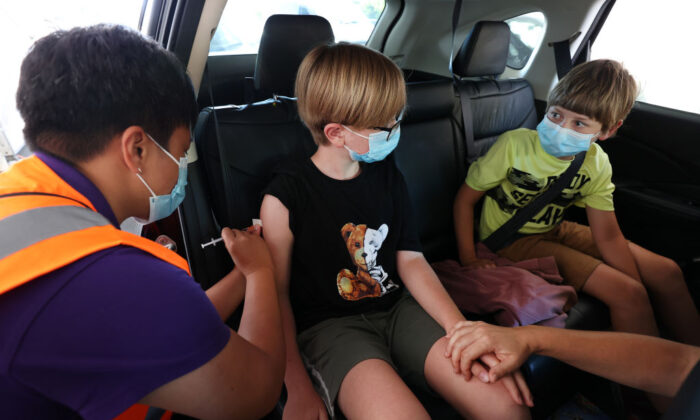 An 11-year-old boy is vaccinated as his brother looks on in support at the drive-through vaccination centre at North Shore Events Centre in Auckland, New Zealand, on Jan. 17, 2022. (Fiona Goodall/Getty Images)