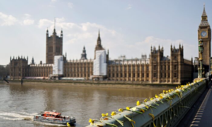 As Britain held a minute's silence to remember the victims of the COVID-19 pandemic, on the second anniversary of the country's first lockdown, flowers are laid at Westminster Bridge in London on March 23, 2022. (Tolga Akmen /AFP via Getty Images)