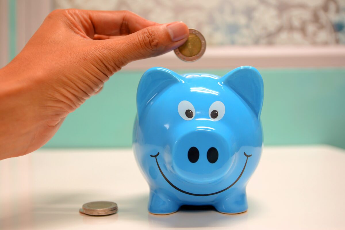 Stock photo of a person putting coins into a piggy bank. (maitree rimthong/Pexels)