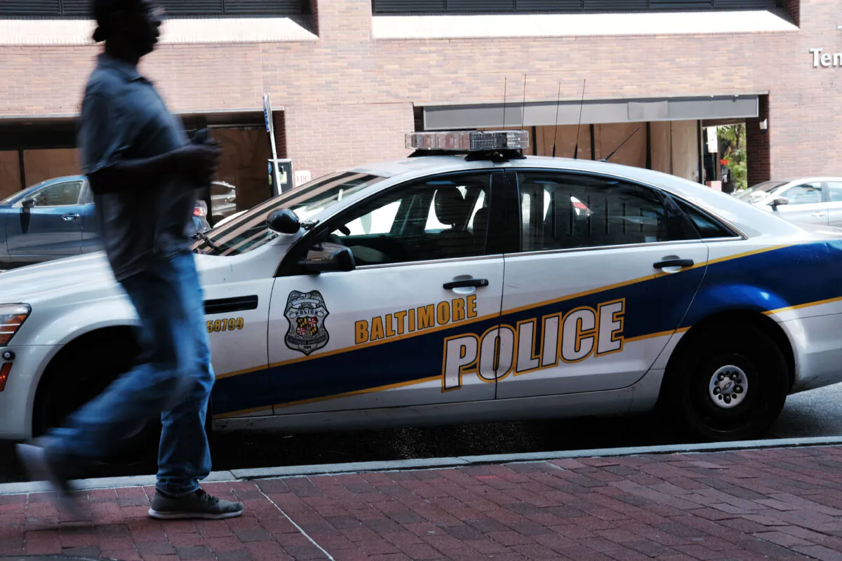 A person walks past a police car on July 28, 2019 in Baltimore, Maryland.  Baltimore has a stubborn crime problem and has one of the highest murder rates in the nation for a city of any size. (Spencer Platt/Getty Images)