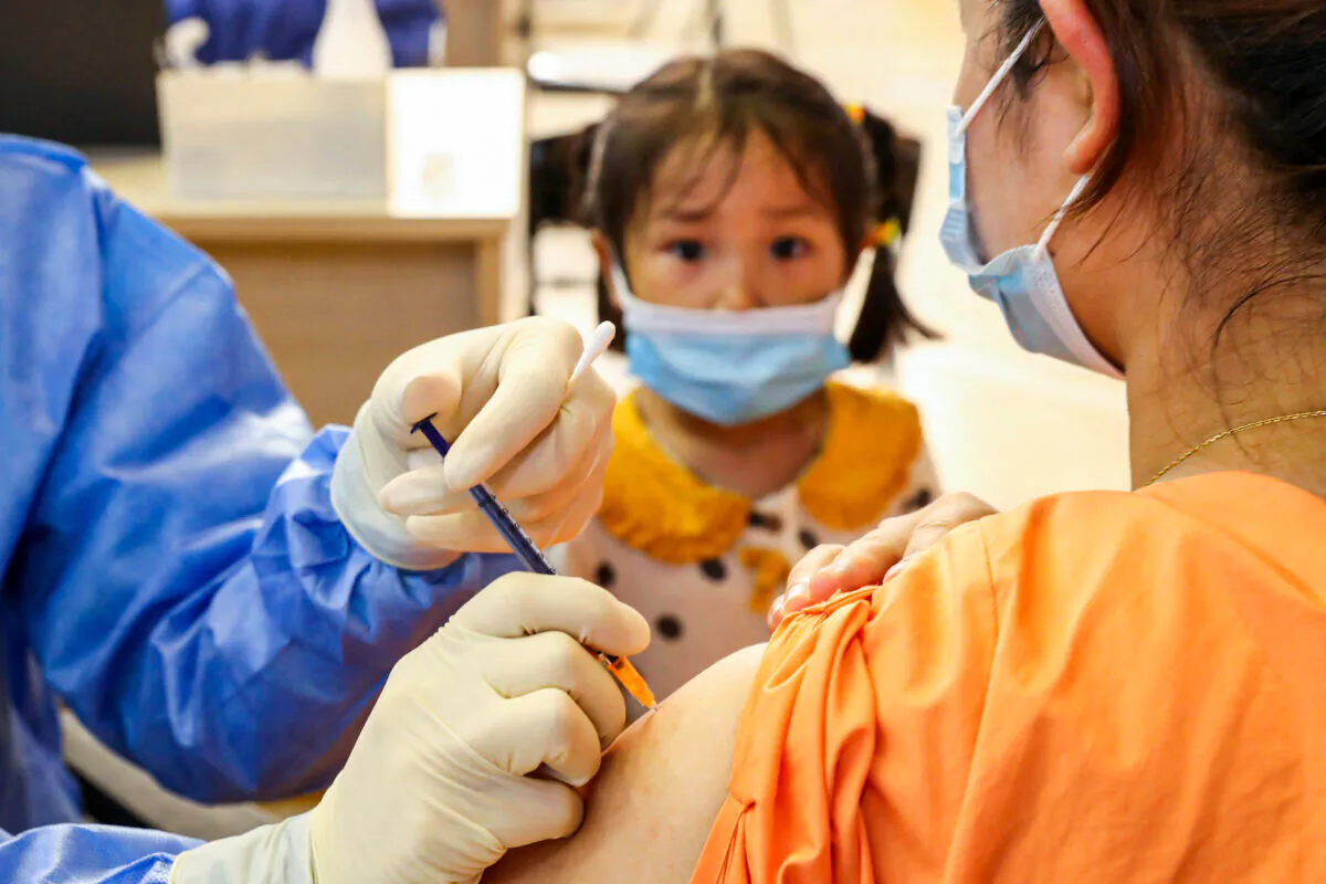 A child looking on as a woman receives the China National Biotec Group (CNBG) COVID-19 vaccine in Nantong, in China's eastern Jiangsu Province, on July 5, 2021. (STR/AFP via Getty Images)