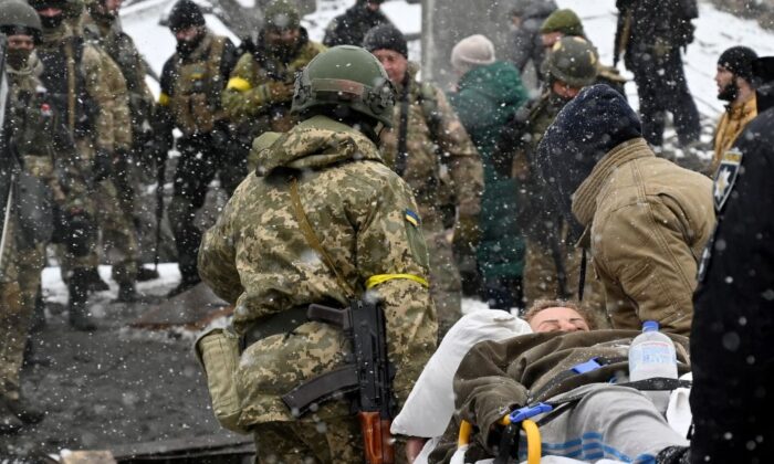 Ukrainian soldiers carry a wounded woman during the evacuation by civilians of the city of Irpin, northwest of Kyiv, Ukraine, on March 8, 2022. (Sergei Supinsky/AFP via Getty Images)