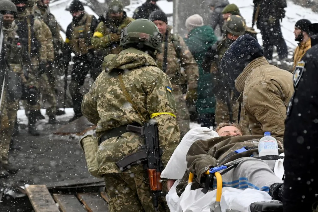 Ukrainian soldiers carry a wounded woman during the evacuation by civilians of the city of Irpin, northwest of Kyiv, Ukraine, on March 8, 2022. (Sergei Supinsky/AFP via Getty Images)