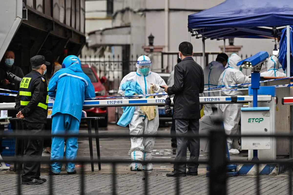 A delivery man (L in blue) is seen arriving to deliver an order outside of a locked down neighbourhood after the detection of new cases of Covid-19 in Huangpu district, in Shanghai on March 17, 2022. (Hector Retamal/AFP via Getty Images)