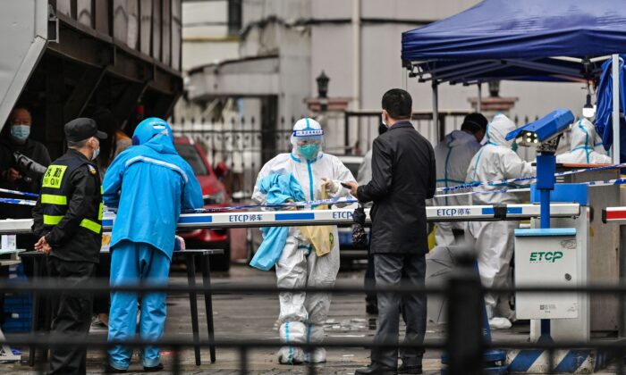 A delivery man (L in blue) is seen arriving to deliver an order outside of a locked down neighbourhood after the detection of new cases of Covid-19 in Huangpu district, in Shanghai on March 17, 2022. (Hector Retamal/AFP via Getty Images)