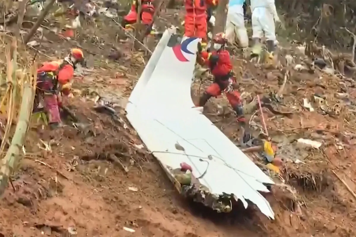 Rescue teams with a piece of the fuselage as they continue to search at the site of a China Eastern passenger jet crash  near Wuzhou, Guangxi region, China. (CCTV via Getty Images/Screenshot via  The Epoch Times)