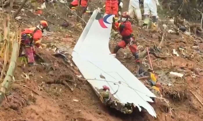 Rescue teams with a piece of the fuselage as they continue to search at the site of a China Eastern passenger jet crash  near Wuzhou, Guangxi region, China. (CCTV via Getty Images/Screenshot via  The Epoch Times)