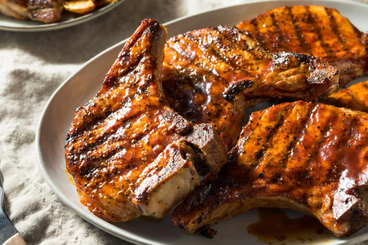 Grilled pork chops topped with a citrusy lemon-garlic relish and served with broccoli. (bhofack2 / iStock / Getty Images Plus)