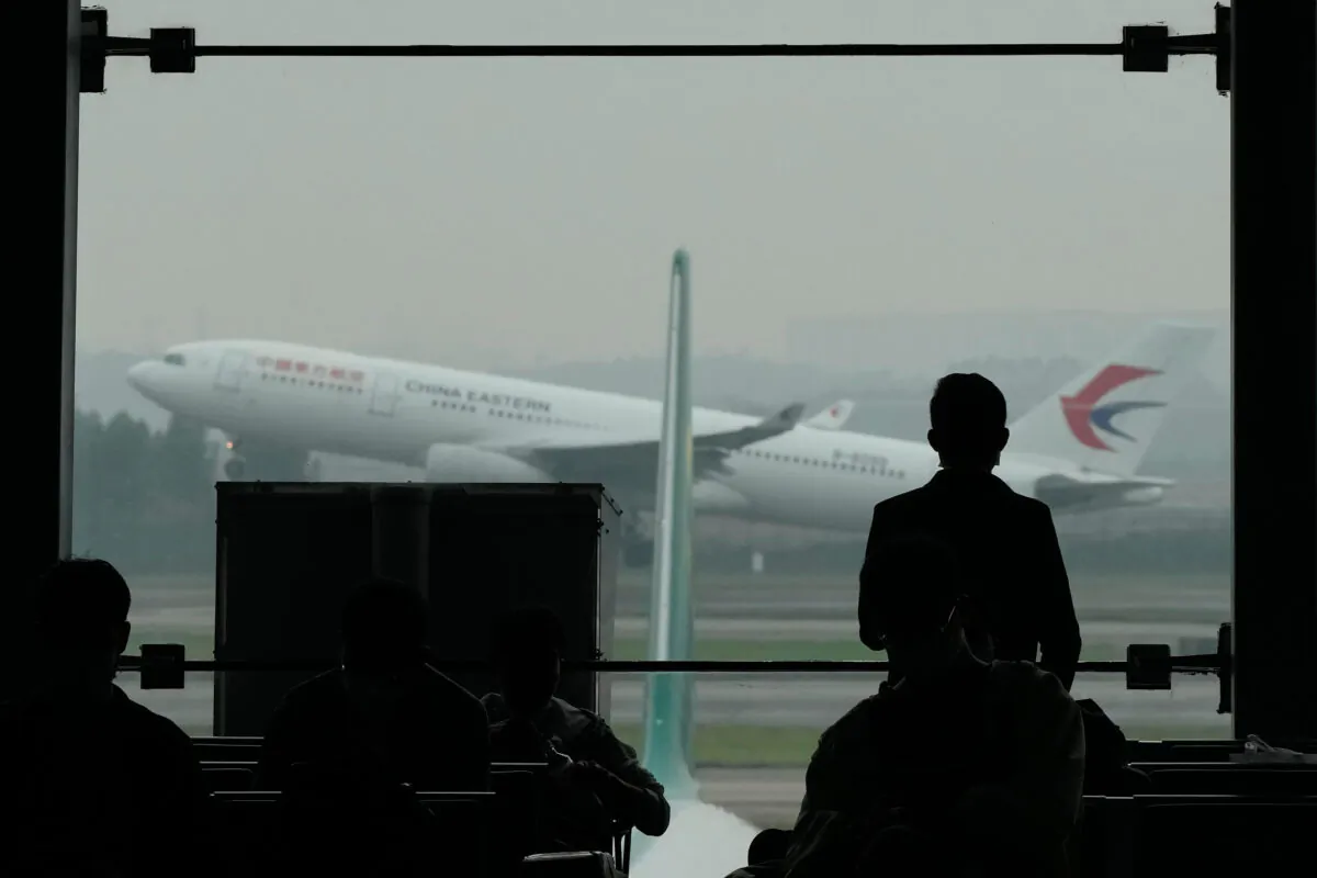 A passenger looks on as a China Eastern flight takes off from the runway of Baiyun Airport on March 25, 2022, in Guangzhou Province. China Eastern, one of China's four major airlines, said Thursday the Shanghai-based carrier and its subsidiaries have grounded a total of 223 Boeing 737-800 aircraft while they investigate possible safety hazards after the crash of its flight MU5735 on March 21. (Ng Han Guan/AP)
