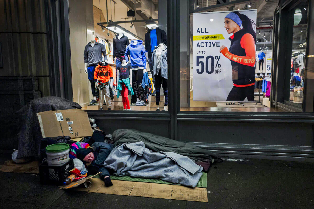 A homeless person sleeps under a blanket outside an Old Navy store window display in New York, on Jan. 11, 2017. (Mark Lennihan/AP Photo)