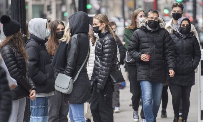 People wear masks as they walk along a street in Montreal on March 27, 2021. (The Canadian Press/Graham Hughes)
