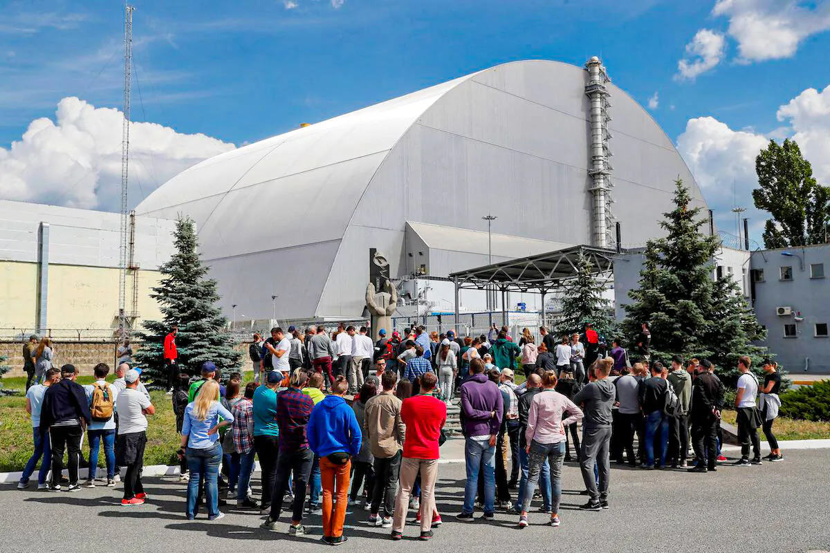 Visitors stand outside the New Safe Confinement (NSC) structure over the old sarcophagus covering the damaged fourth reactor at the Chernobyl Nuclear Power Plant, in Chernobyl, Ukraine June 2, 2019. (Valentyn Ogirenko/Reuters)