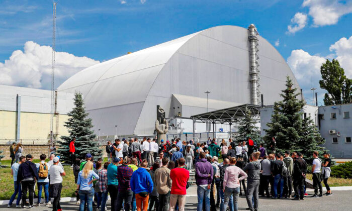 Visitors stand outside the New Safe Confinement (NSC) structure over the old sarcophagus covering the damaged fourth reactor at the Chernobyl Nuclear Power Plant, in Chernobyl, Ukraine June 2, 2019. (Valentyn Ogirenko/Reuters)