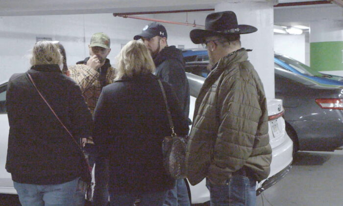 Oath Keepers founder Stewart Rhodes (R) looks on as Proud Boys chairman Enrique Tarrio (L) speaks with attorney Kellye SoRelle and others at a parking garage meeting in Washington D.C. on Jan. 5, 2021. Rhodes says he merely shook Tarrio’s hand and did not have any conversation. (Saboteur Media/Handout via REUTERS)