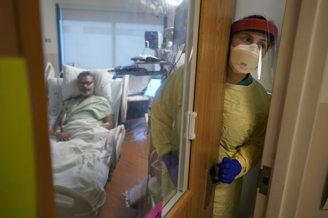 Registered nurse Rachel Chamberlin steps out of an isolation room where Fred Rutherford recovers from COVID-19 at the Dartmouth-Hitchcock Medical Center, in Lebanon, N.H., on Jan. 3, 2022. (Steven Senne/AP Photo)