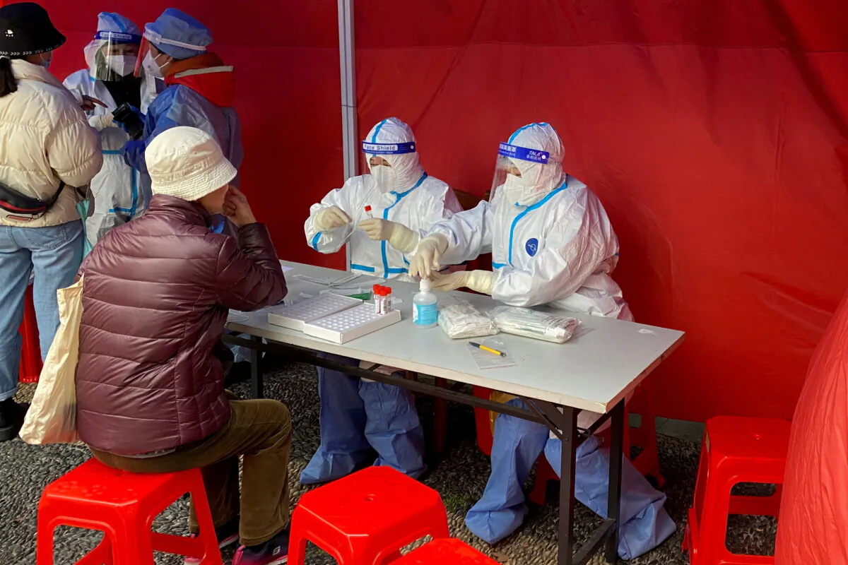 Medical workers in protective suits prepare to take a sample for a nucleic acid test for a resident at a makeshift testing site, following a COVID-19 outbreak, at a residential compound in Shanghai, China March 20, 2022. (David Stanway/Reuters)