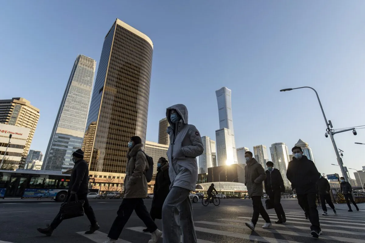 Pedestrians cross a road in front of buildings in the central business district in Beijing, China, on Nov. 23, 2021. China's marked economic slowdown in the second half of the year is testing the central bank's policy mettle and dividing economists over whether more aggressive action is needed to avoid a deeper downturn. (Qilai Shen/Bloomberg via Getty Images)