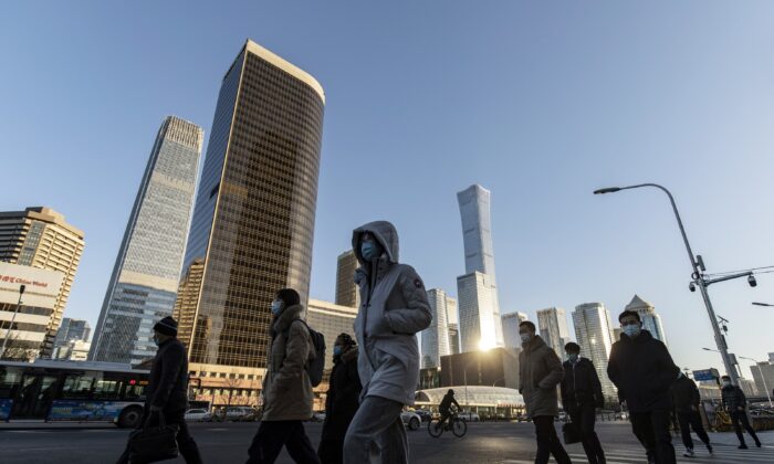 Pedestrians cross a road in front of buildings in the central business district in Beijing, China, on Nov. 23, 2021. China's marked economic slowdown in the year's second half is testing the central bank's policy mettle and dividing economists over whether more aggressive action is needed to avoid a deeper downturn. (Qilai Shen/Bloomberg via Getty Images)