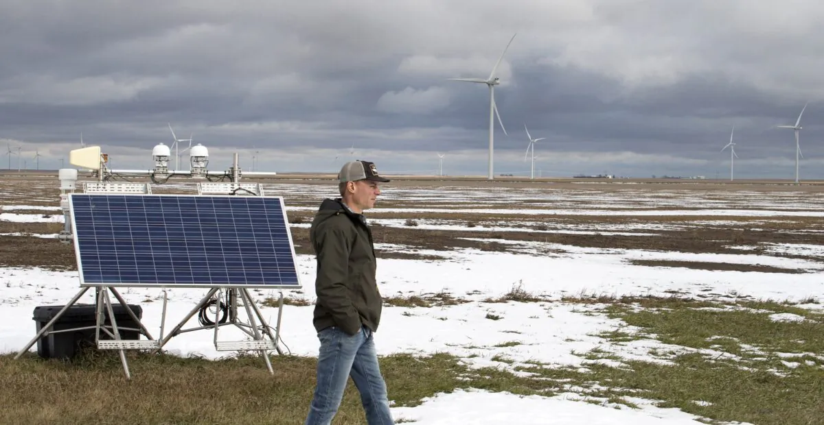 A farmer walks past solar panel and wind energy projects close to his farm near Vulcan, Alta., in a file photo. (The Canadian Press/Larry MacDougal)
