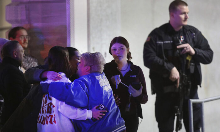 People embrace after being reunited as a police officer stands by following a shooting at Fashion Outlets of Chicago mall in Rosemont, Ill., on March 25, 2020. (Chris Sweda/Chicago Tribune/TNS)