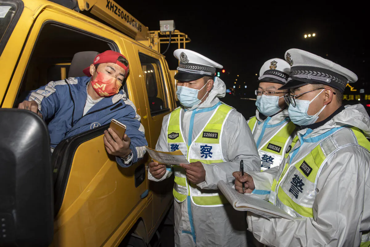 Police officers are checking information with a truck driver (L) at a checkpoint in Ningbo in eastern China's Zhejiang Province on Dec. 18, 2021. (STR/AFP via Getty Images)