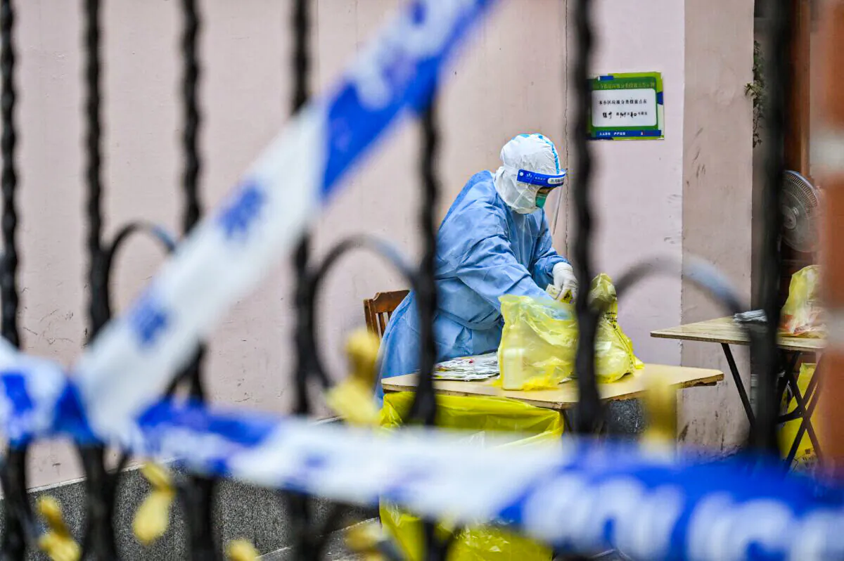 A health worker goes through a bag in a compound as residents are tested for COVID-19 inside a compound in Jing'an district, in Shanghai on March 29, 2022. (Hector Retamal/AFP via Getty Images)