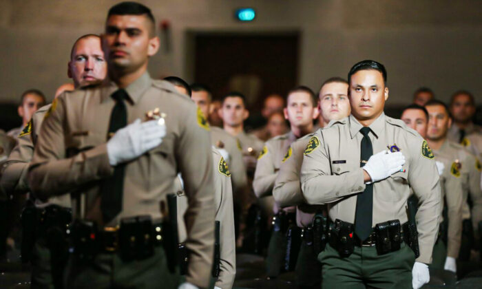 Graduates of Los Angeles County Sheriff's Department Academy Class 451 stand for the pledge of allegiance at their graduation ceremony at East Los Angeles College amid the COVID-19 pandemic in Monterey Park, Calif., on Aug. 21, 2020. (Mario Tama/Getty Images)