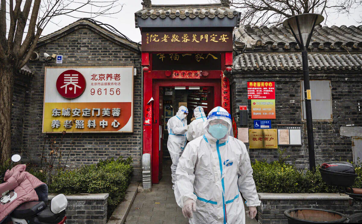 Health workers wear protective suits as they stand outside a seniors care home in a traditional courtyard house where they were performing nucleic acid test to detect COVID-19 on local residents in Beijing, China, on March 25, 2022. (Kevin Frayer/Getty Images)