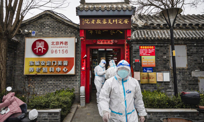 Health workers wear protective suits as they stand outside a seniors care home in a traditional courtyard house where they were performing nucleic acid test to detect COVID-19 on local residents in Beijing, China, on March 25, 2022. (Kevin Frayer/Getty Images)