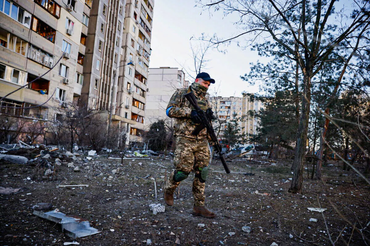 A member of the Ukrainian military surveys an area next to a residential building that was hit by an intercepted missile, in Kyiv, Ukraine, on March 17, 2022. (Thomas Peter/Reuters)