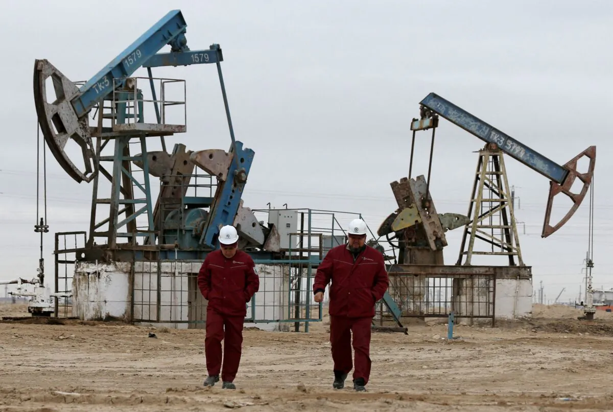Workers walk as oil pumps are seen in the background in the Uzen oil and gas field in the Mangistau Region of Kazakhstan, on Nov.13, 2021. (Pavel Mikheyev/Reuters)