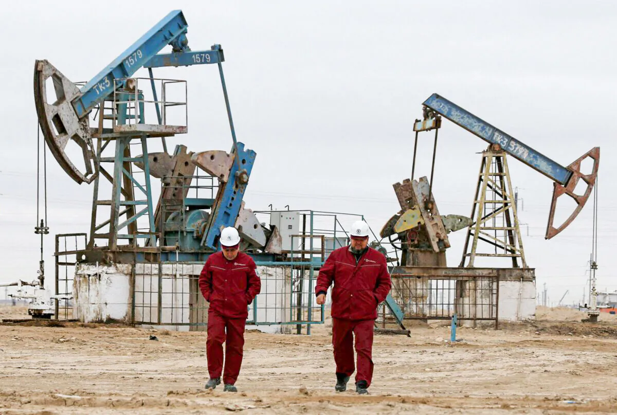 Workers walk as oil pumps are seen in the background in the Uzen oil and gas field in the Mangistau Region of Kazakhstan, on Nov.13, 2021. (Pavel Mikheyev/Reuters)
