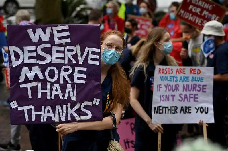 Nurses and midwives hold placards during a nurses’ strike rally at NSW Parliament House in Sydney, March 31, 2022. (AAP Image/Bianca De Marchi)