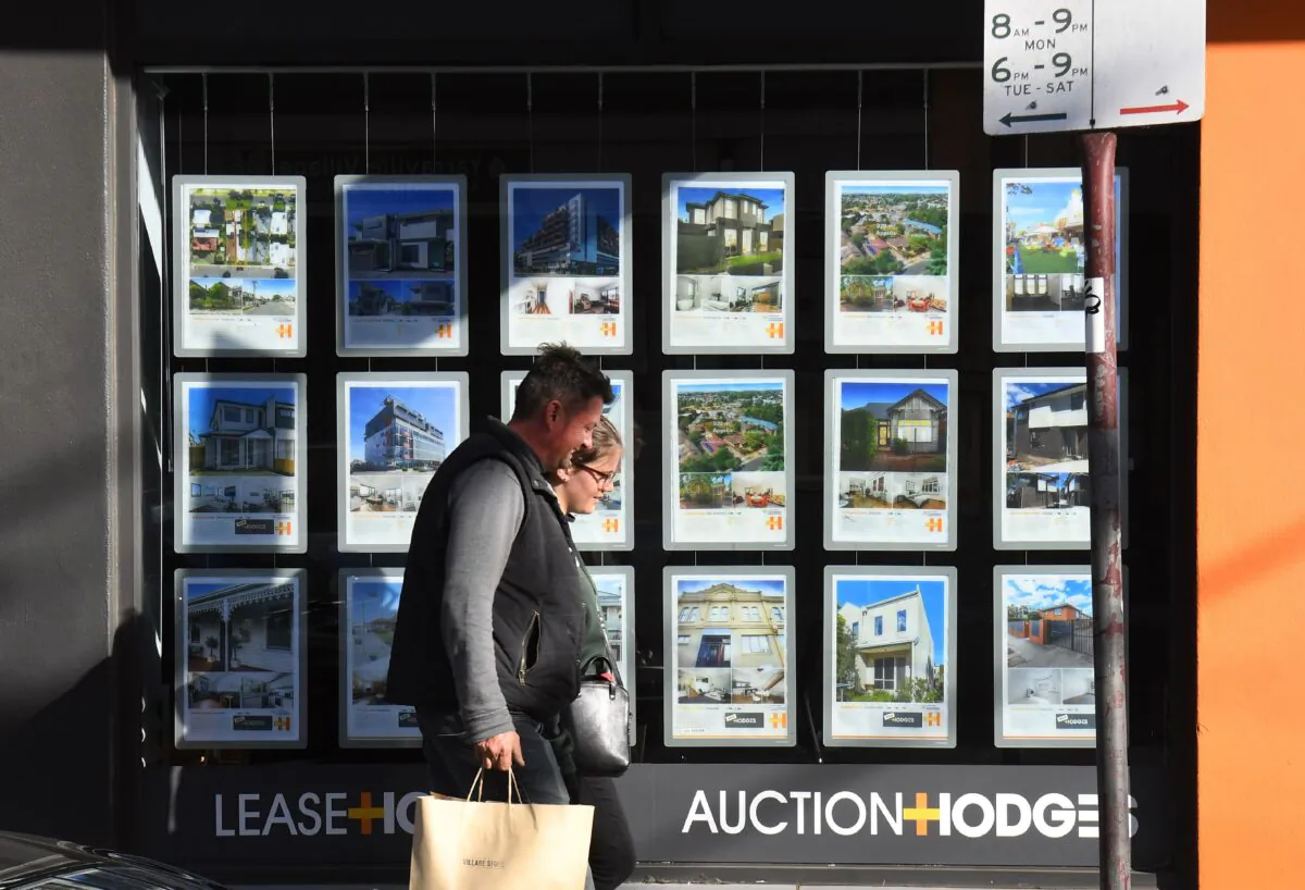 A couple walks past a real estate agent's window advertising houses for sale and auction in Melbourne on May 1, 2019. (WILLIAM WEST/AFP via Getty Images)