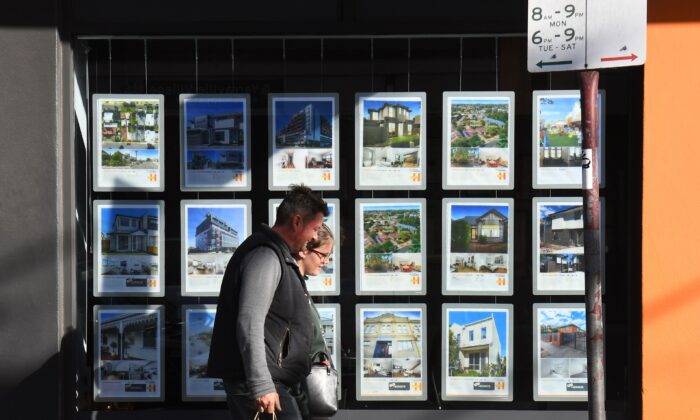 A couple walks past a real estate agent's window advertising houses for sale and auction in Melbourne on May 1, 2019. (WILLIAM WEST/AFP via Getty Images)