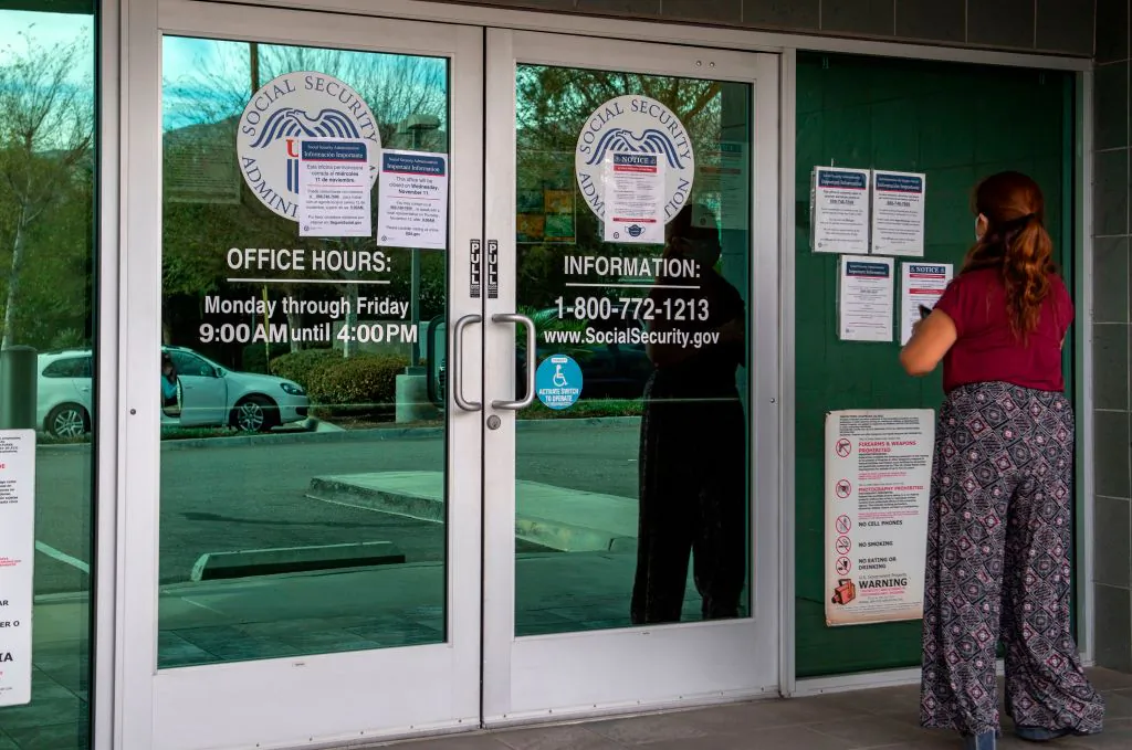 A woman looks at notices regarding measures in place during the coronavirus pandemic displayed outside a US Social Security Administration building, November 5, 2020, in Burbank, California. (Photo by VALERIE MACON / AFP) (Photo by VALERIE MACON/AFP via Getty Images)