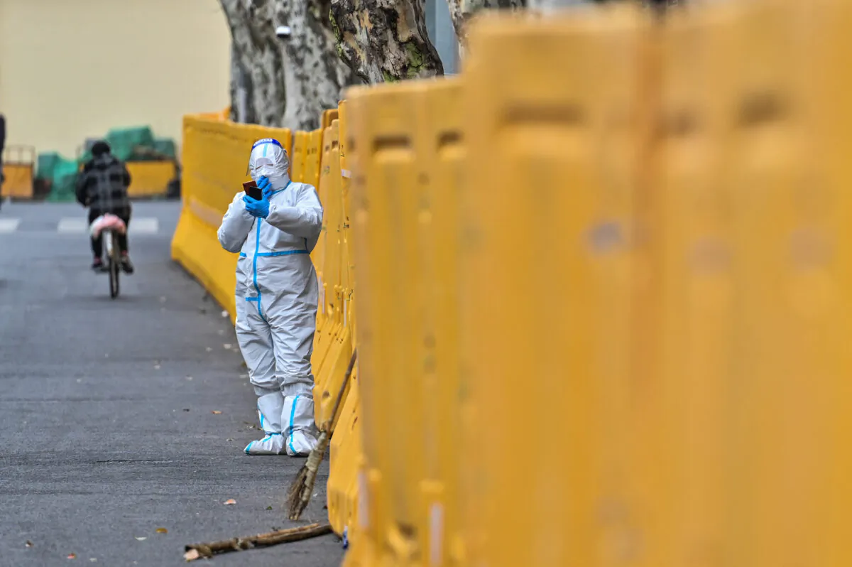 A worker wearing protective gear stands next to barriers during lockdown in Jing'an district, Shanghai, on March 31, 2022. (Hector Retamal/AFP via Getty Images)