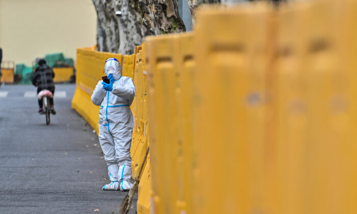 2022 年 3 月 31 日，上海静安区封锁期间，一名身穿防护装备的工人站在路障旁。（赫克托·雷塔马尔/法新社通过 Getty Images）