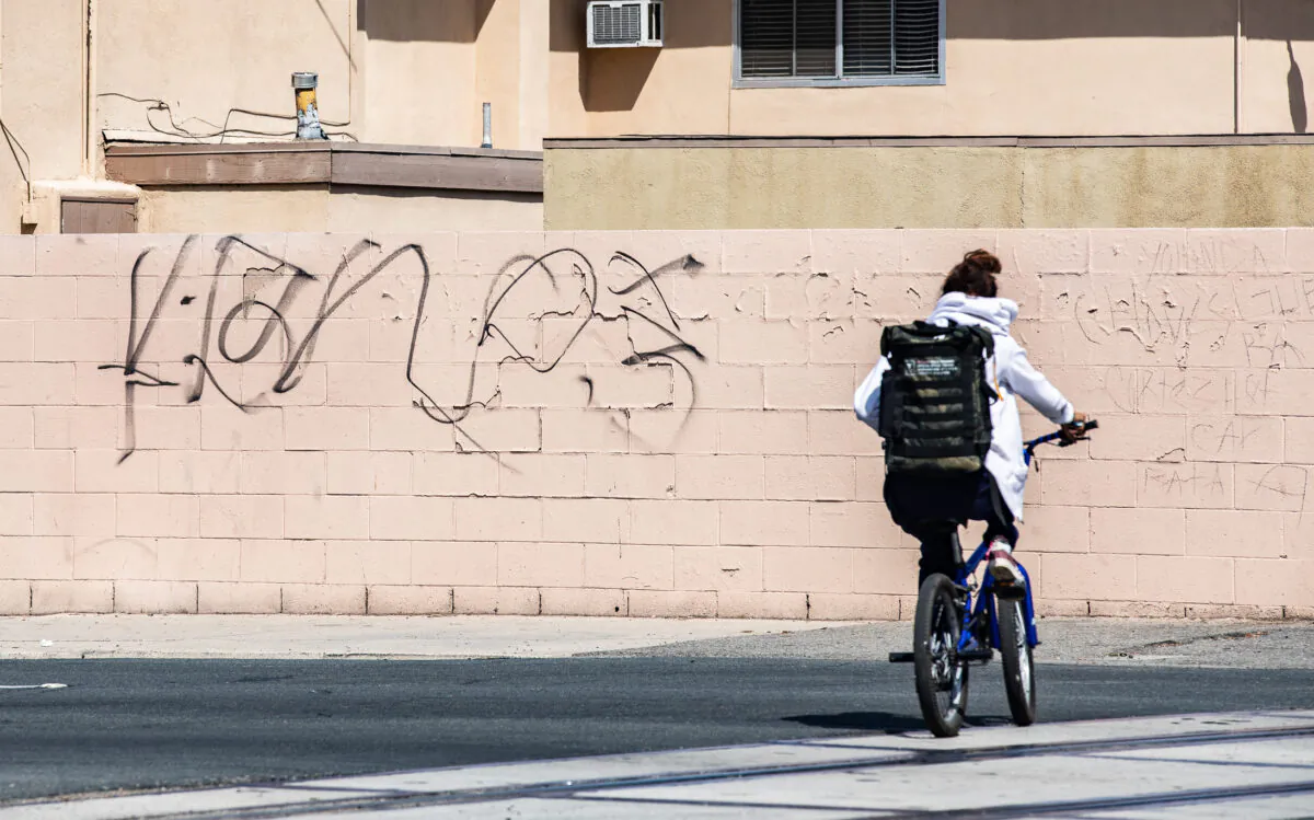 A file photo of a bicyclist riding next to graffiti in Southern California, on March 25, 2022. (John Fredricks/The Epoch Times)