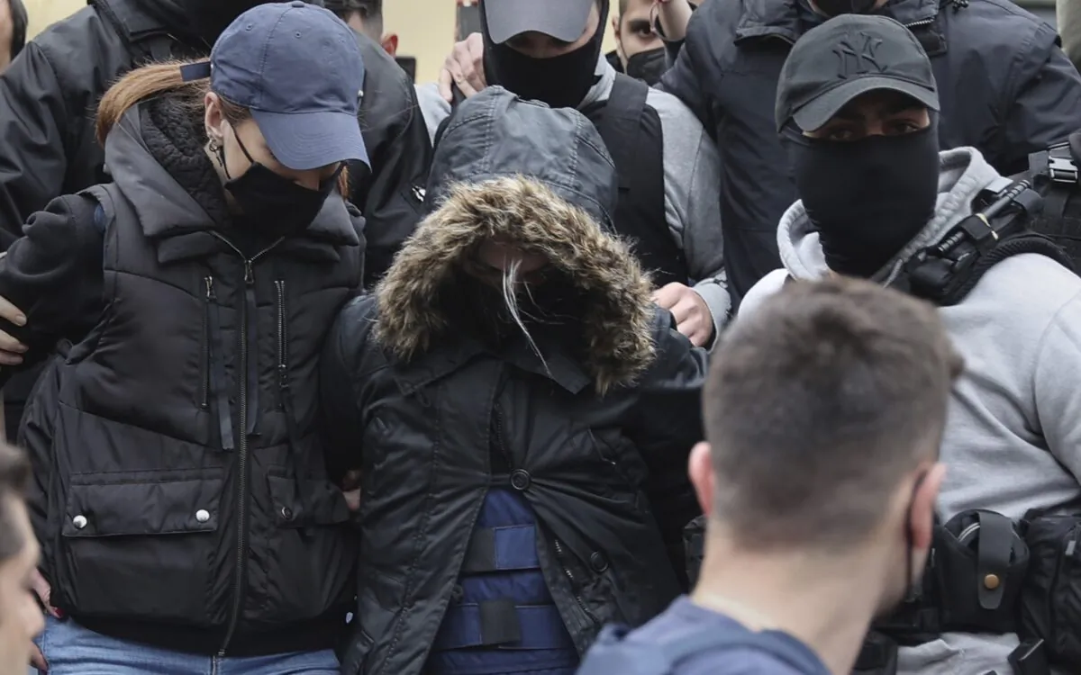 A 33-year-old woman (C), with the hooded jacket, is escorted by police as she leaves the court in Athens, Greece, on March 31, 2022. (John Liakos/InTime News via AP)