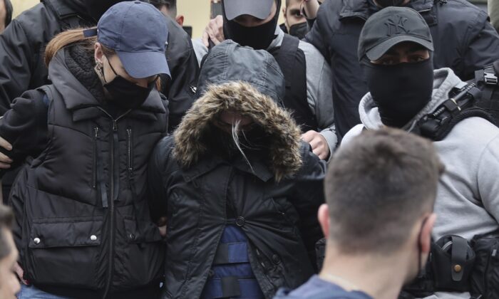 A 33-year-old woman (C), with the hooded jacket, is escorted by police as she leaves the court in Athens, Greece, on March 31, 2022. (John Liakos/InTime News via AP)