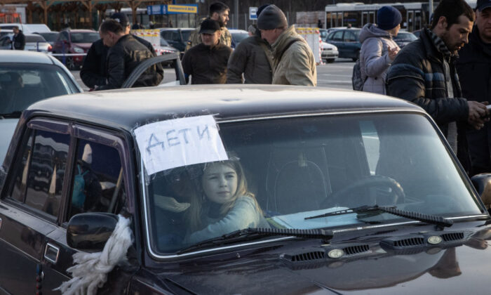 2022 年 3 月 25 日，在乌克兰扎波罗热的马里乌波尔和梅利托波尔，一个女孩在一个由汽车和公共汽车组成的车队的疏散点等候。（克里斯麦格拉思/盖蒂图片社）
