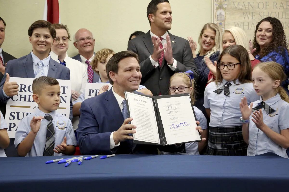 Florida Gov. Ron DeSantis displays the signed Parental Rights in Education bill flanked by elementary school students during a news conference at Classical Preparatory school in Shady Hills, Fla., on March 28, 2022. (Douglas R. Clifford/Tampa Bay Times via AP)
