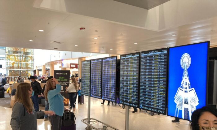 Travelers at Seattle-Tacoma International Airport check the status of flights, including a few that were canceled, on displays inside a gate terminal in Seattle on April 1, 2022. (Ted S. Warren/AP Photo)