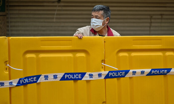 A man stands behind a barrier during the  lockdown in Jing'an district in Shanghai on March 31, 2022. (Hector Retamal/AFP via Getty Images)